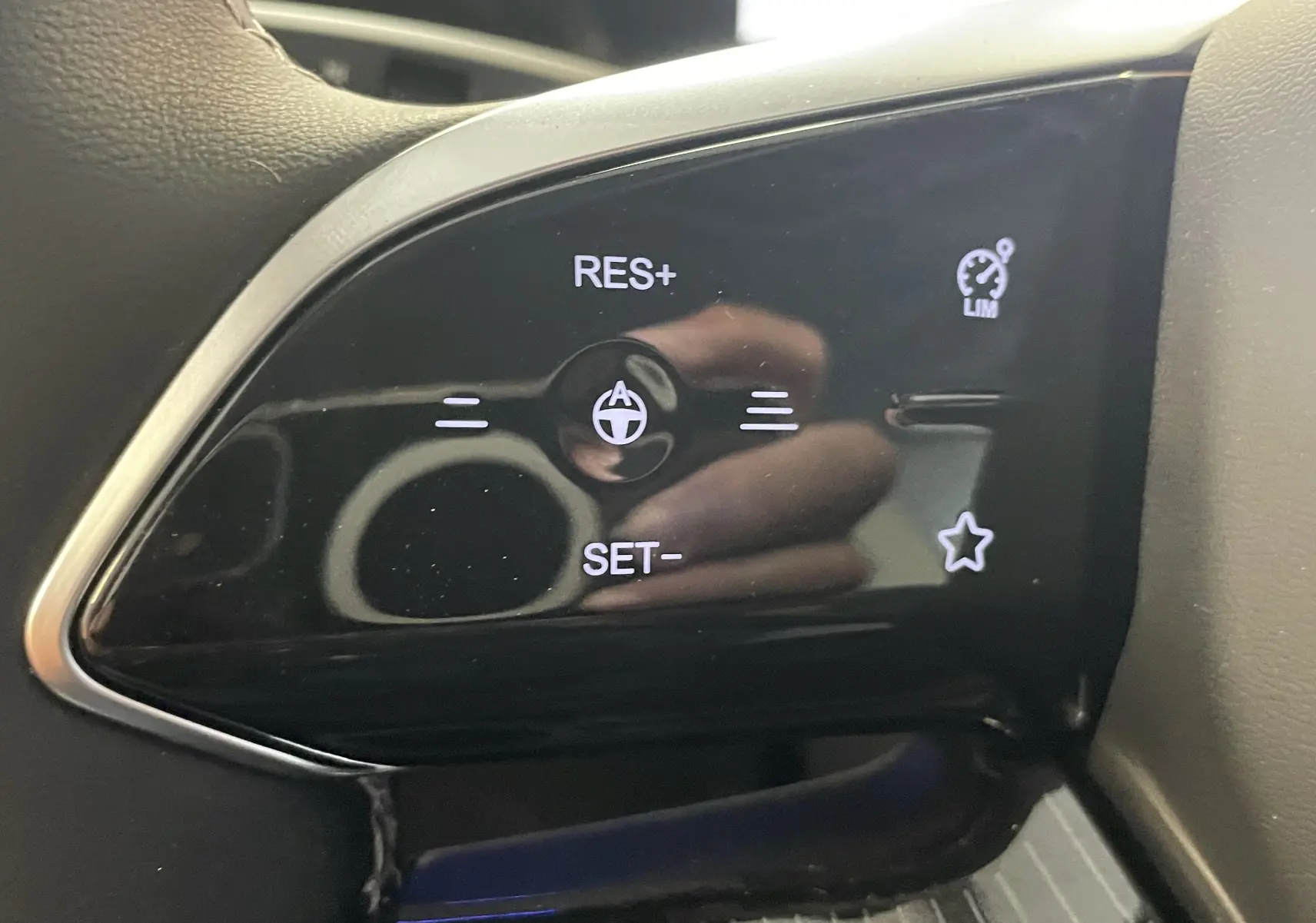 Gros plan sur les commandes de régulateur de vitesse au volant du JAECOO J5, finition noire brillante.