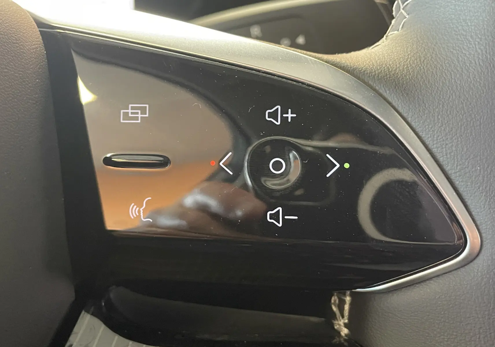 Gros plan sur les commandes de volume et de navigation multimédia sur le volant en cuir noir du JAECOO J5 Phantom Grey.