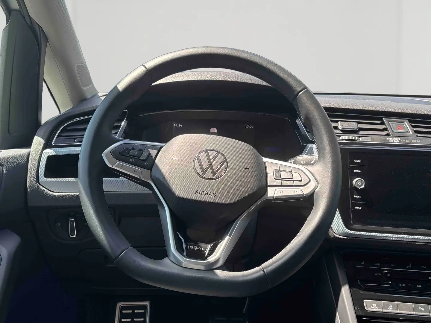 Vue intérieure centrée sur le volant cuir multifonctions du Volkswagen Touran blanc, avec tableau de bord et écran tactile visible.