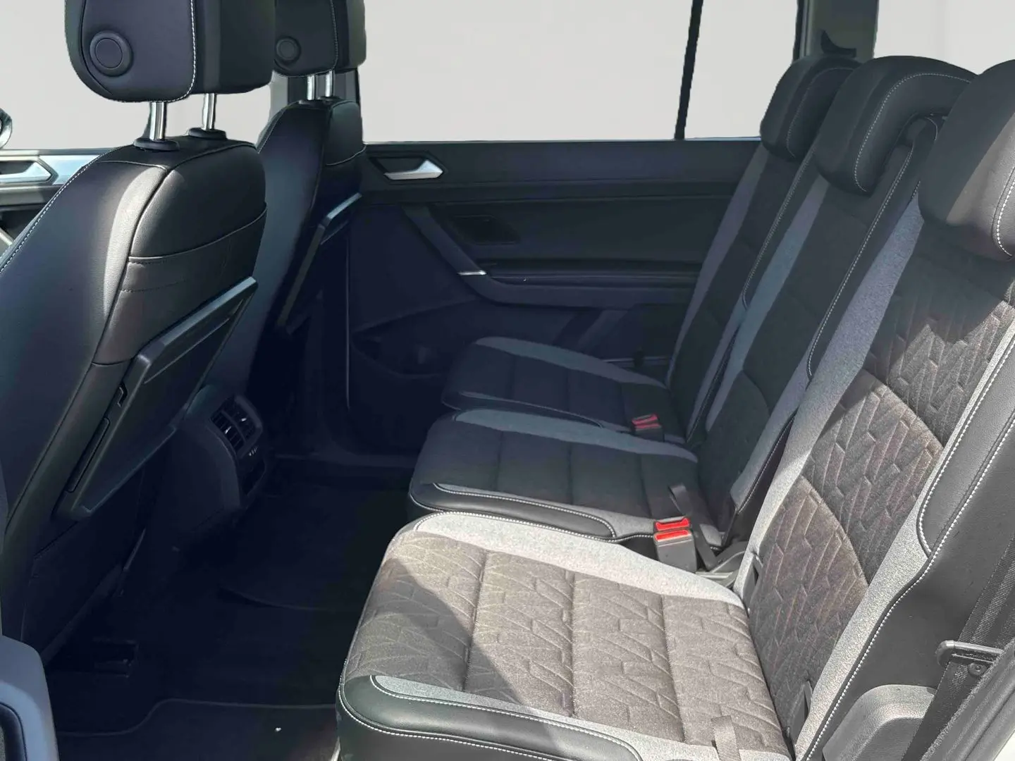 Vue latérale intérieure sur la banquette arrière noire et grise du Volkswagen Touran 2025 avec appuie-têtes ajustables.