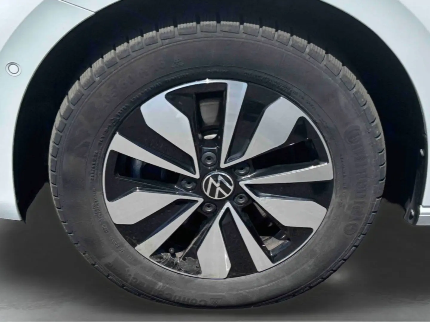 Gros plan sur la jante alliage bicolore noire et argent du côté gauche d’un Volkswagen Touran blanc.
