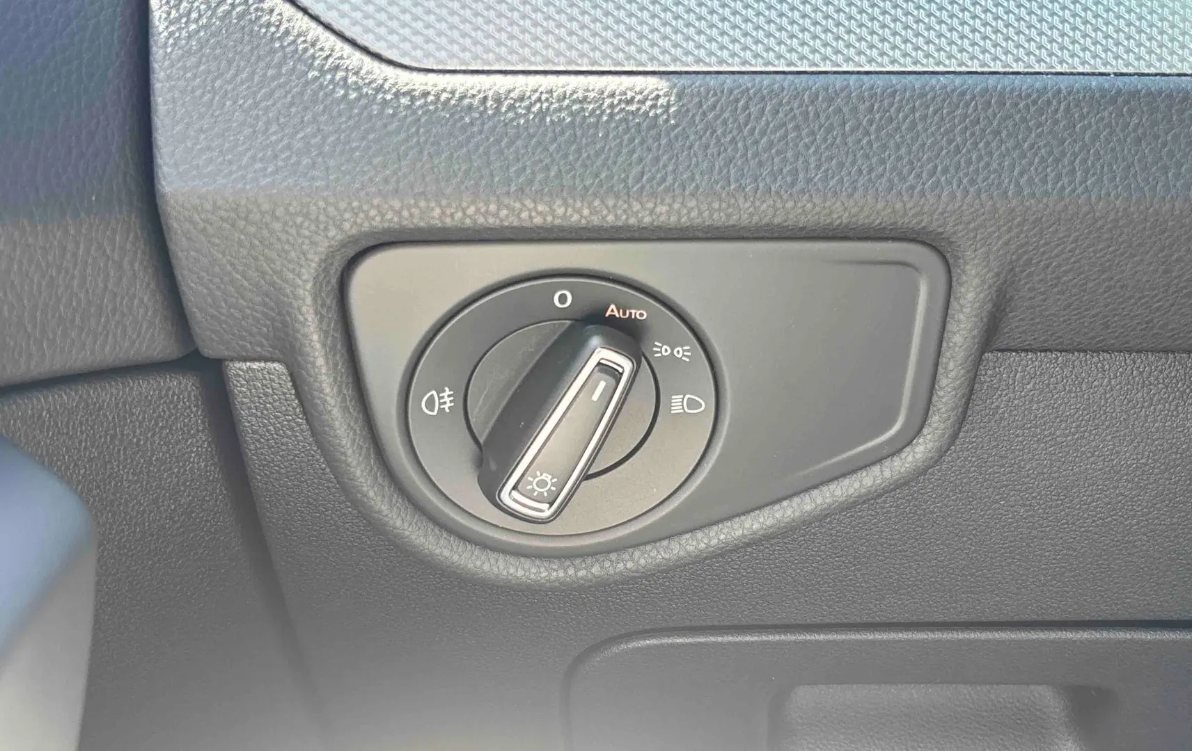 Gros plan sur la commande d'éclairage noire intégrée au tableau de bord du Volkswagen Touran blanc.