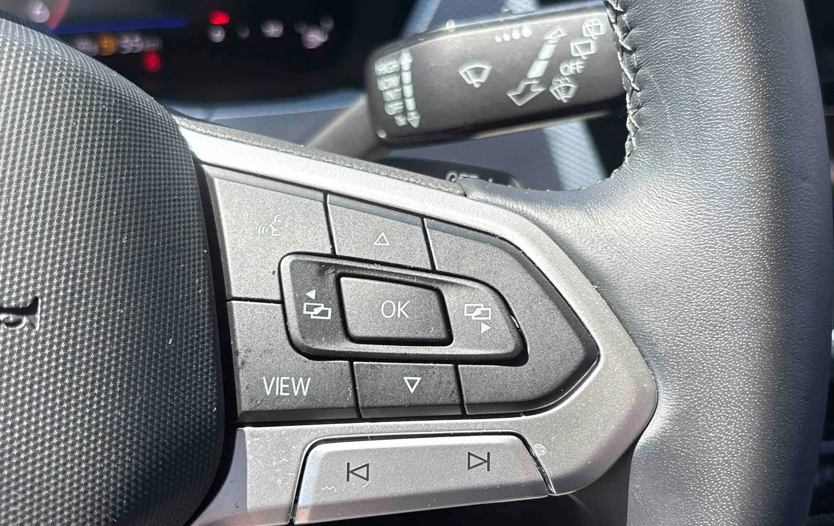 Gros plan sur le volant cuir multifonctions du Volkswagen Touran 2025, boutons de commande visibles côté gauche.