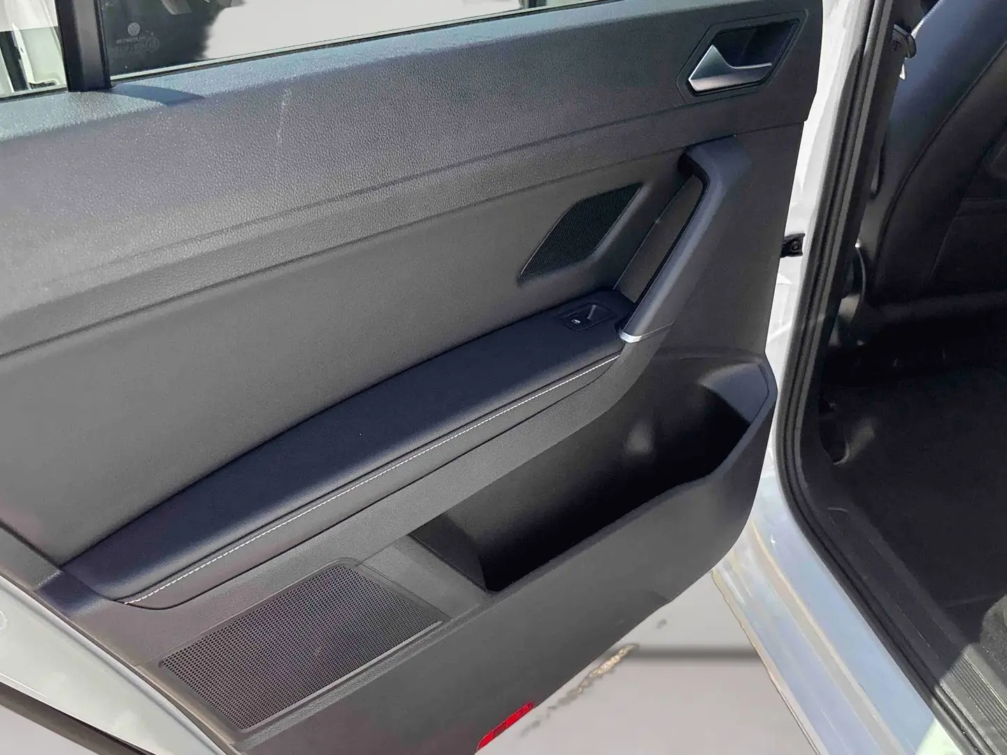 Vue rapprochée de la porte avant gauche ouverte du Volkswagen Touran blanc, montrant la garniture intérieure noire et la commande de fenêtre.