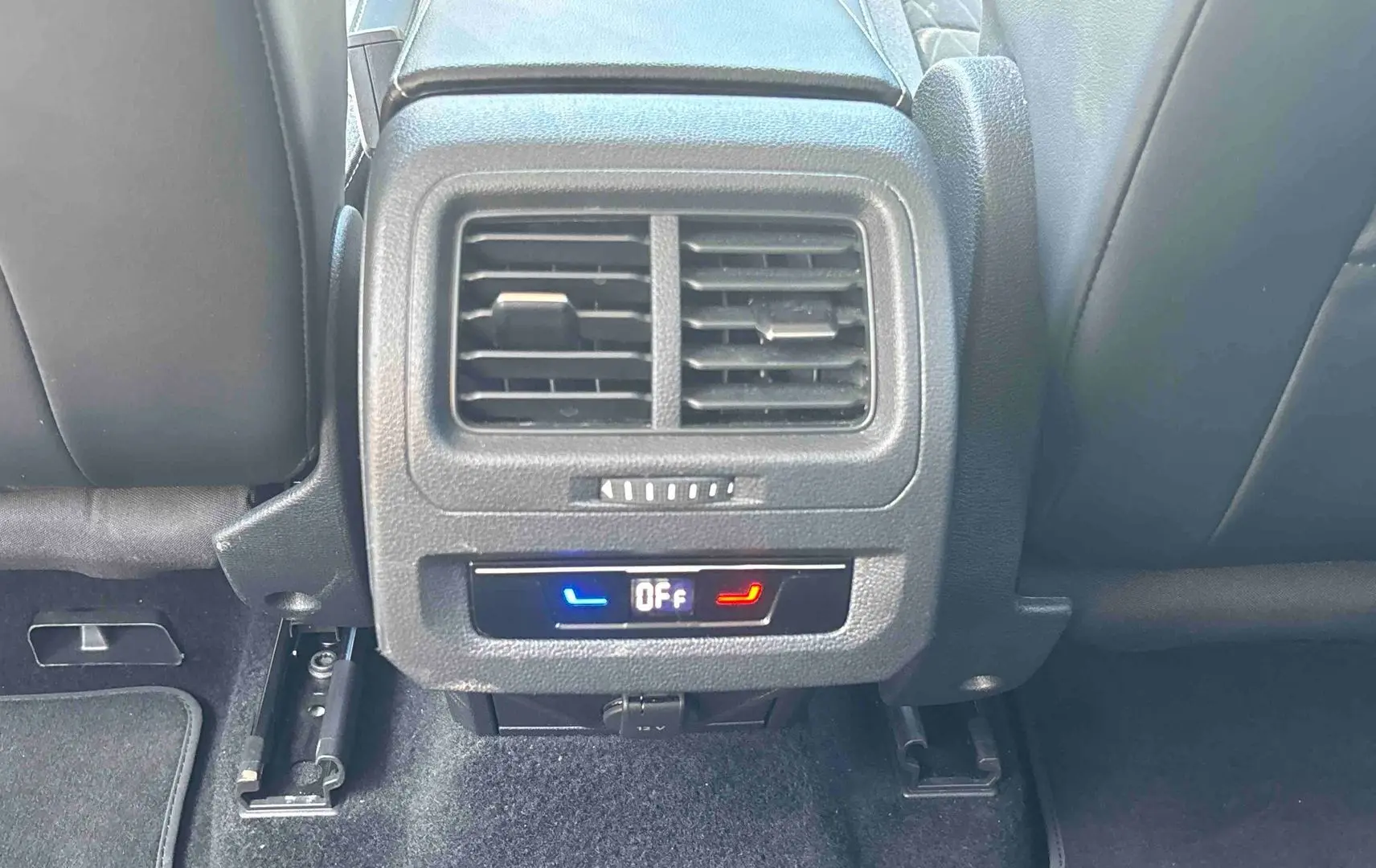 Vue rapprochée de la console arrière du Volkswagen Touran blanc 2025, montrant les aérateurs et commandes de climatisation.
