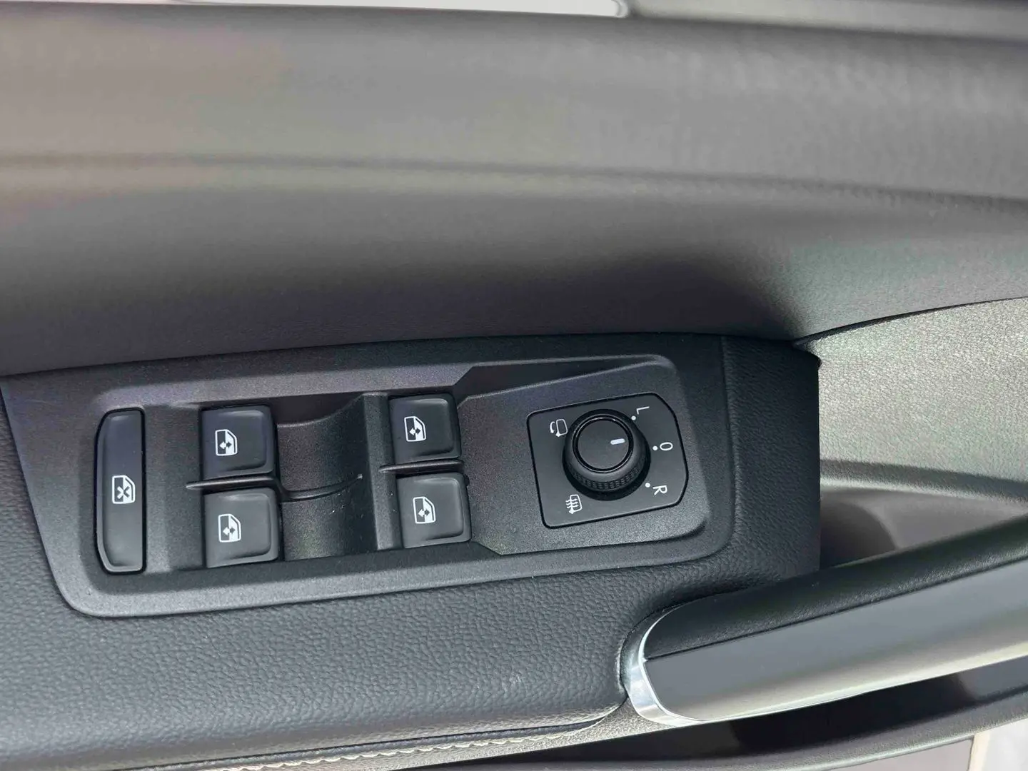 Gros plan sur les commandes des vitres et rétroviseurs côté gauche intérieur du Volkswagen Touran blanc.