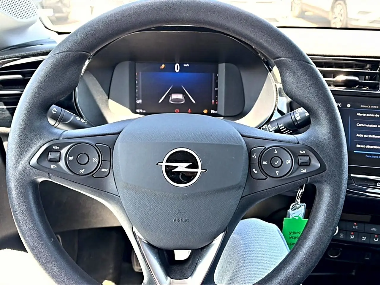 Vue rapprochée du volant noir multifonction d'une Opel Corsa 1.2 turbo 100 edition avec tableau de bord numérique.
