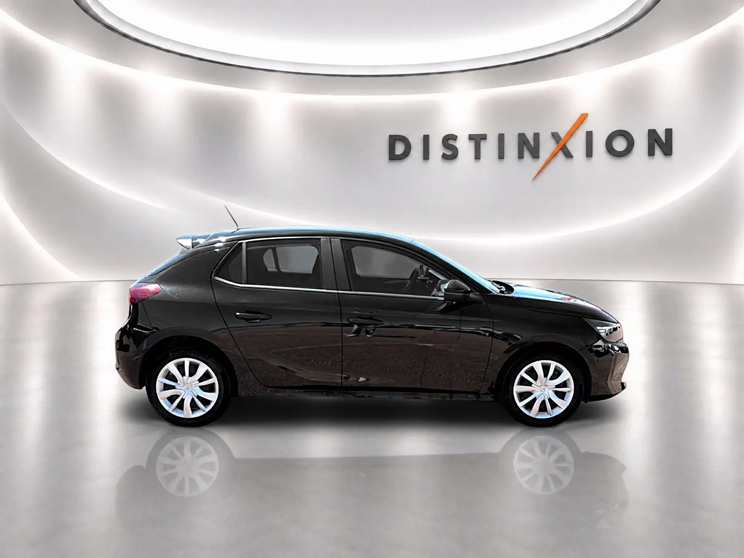 Profil droit d'une Opel Corsa noire 2025 dans un showroom lumineux avec logo Distinxion en arrière-plan.