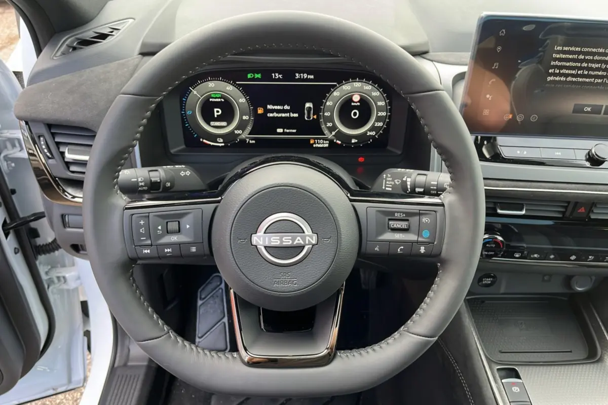 Vue centrée sur le volant cuir multifonctions noir du Nissan Qashqai E-POWER 2026 avec tableau de bord numérique et écran tactile.