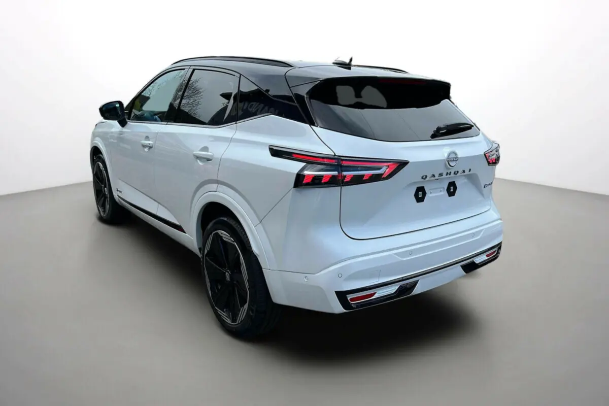 Vue 3/4 arrière gauche du Nissan Qashqai blanc nacré avec toit noir et jantes noires 20 pouces, feux arrière LED allumés.