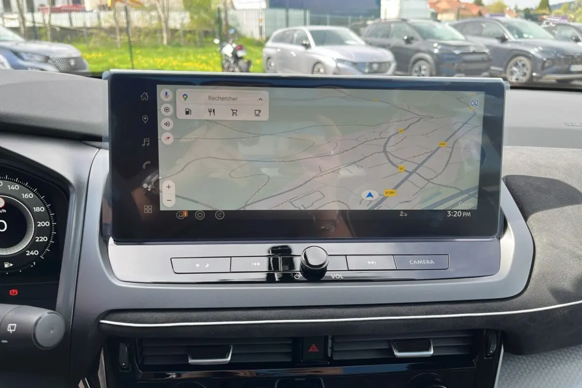 Vue rapprochée de l’écran tactile central du tableau de bord du Nissan Qashqai blanc nacré 2026 avec navigation GPS affichée.