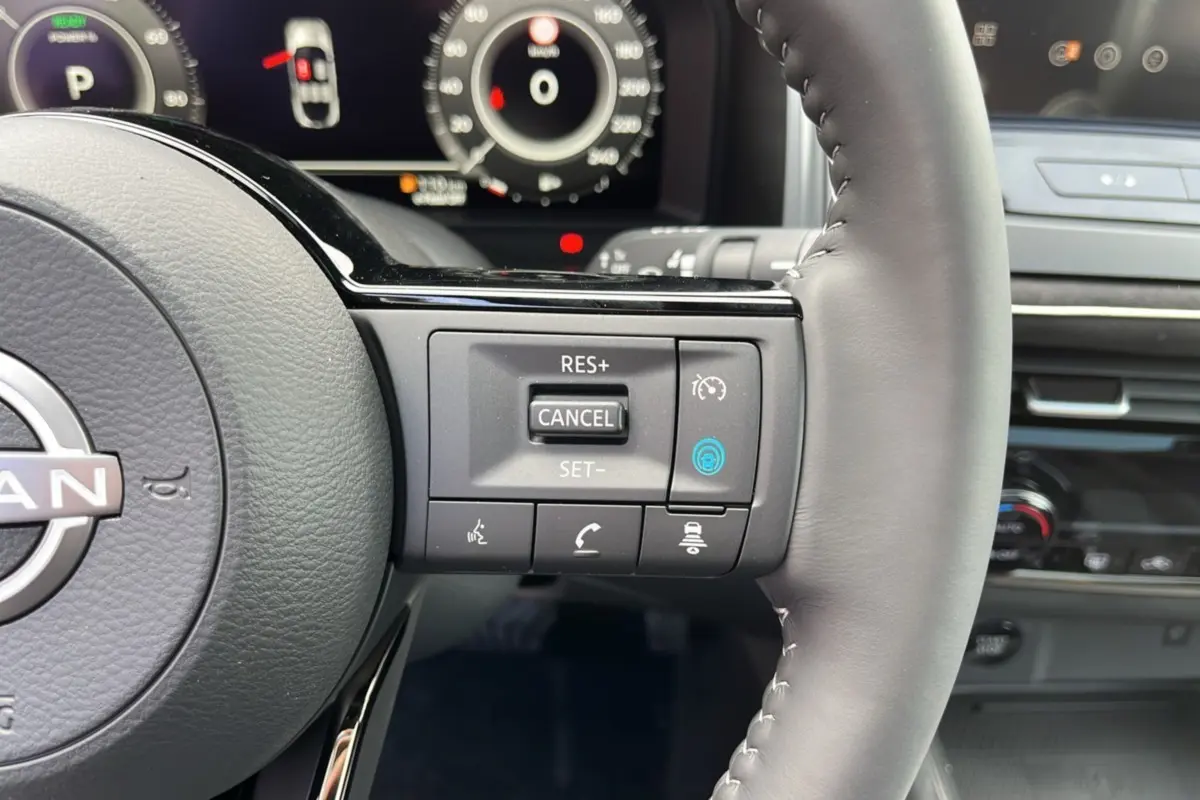 Gros plan sur le volant cuir multifonctions du Nissan Qashqai E-POWER 2026 avec commandes de régulateur et tableau de bord numérique.