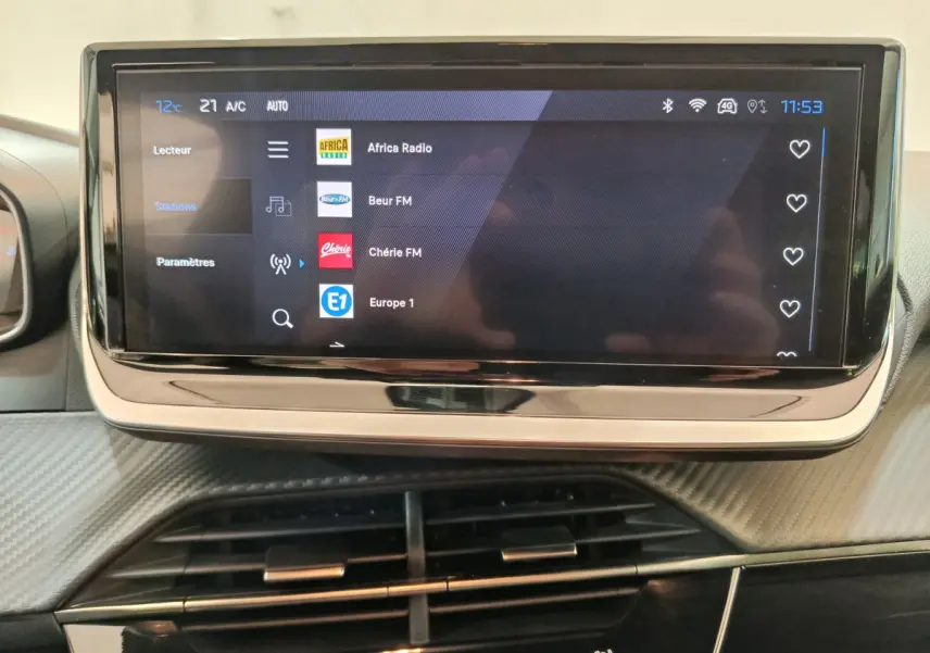 Écran tactile central de la Peugeot 208 PureTech 100 S&S Allure 2025 affichant une liste de stations radio.