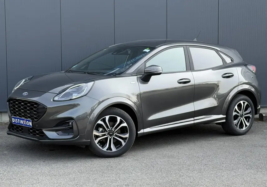 Ford Puma Ecoboost 155 ST Line gris magnétique en 3/4 avant droit, avec jantes alliage et calandre noire distinctive.