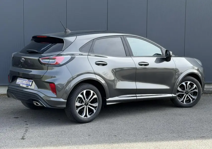 Ford Puma Ecoboost gris magnétique en 3/4 arrière droit avec jantes alliage et hayon électrique visible.