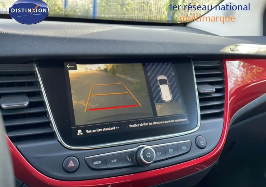 Vue rapprochée de l’écran multimédia de l’Opel Crossland 2023 avec caméra de recul et tableau de bord rouge brillant.