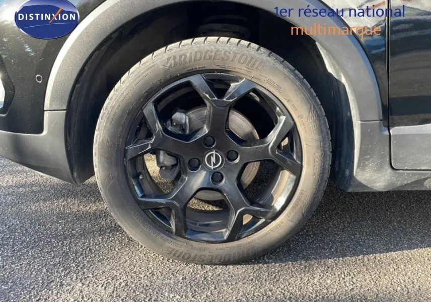 Gros plan sur la roue avant droite noire avec jante noire du SUV Opel Crossland noir Karbon Metal.