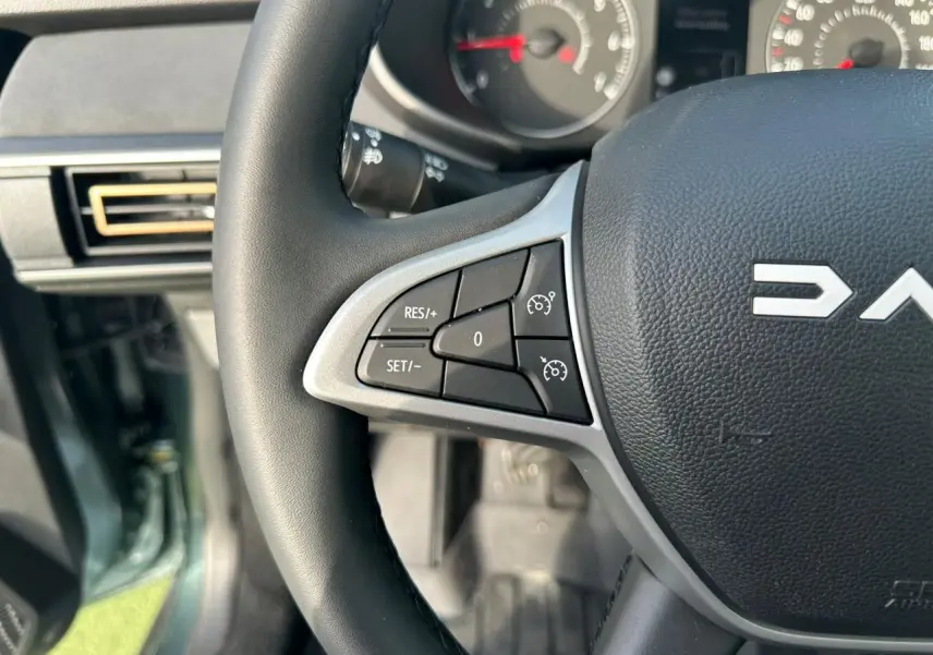 Gros plan sur le volant noir de la Dacia Sandero III Stepway 2025 avec commandes de régulateur de vitesse.