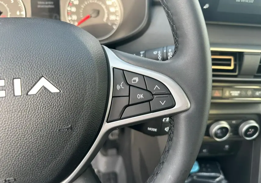 Gros plan sur le volant noir avec commandes multifonctions et tableau de bord de la Dacia Sandero III Stepway.