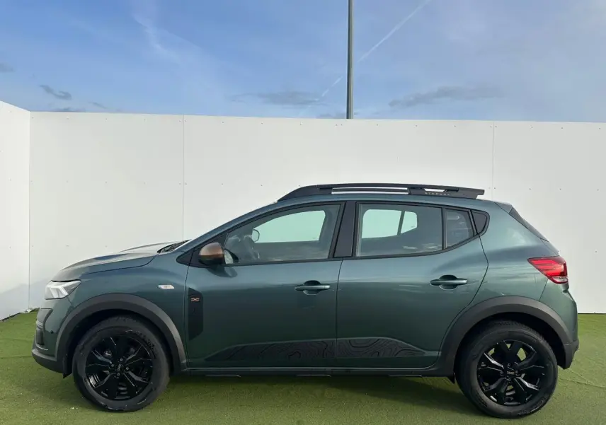 Vue de profil côté gauche d'une Dacia Sandero III Stepway 2025 vert cèdre avec jantes noires et détails brun cuivré.