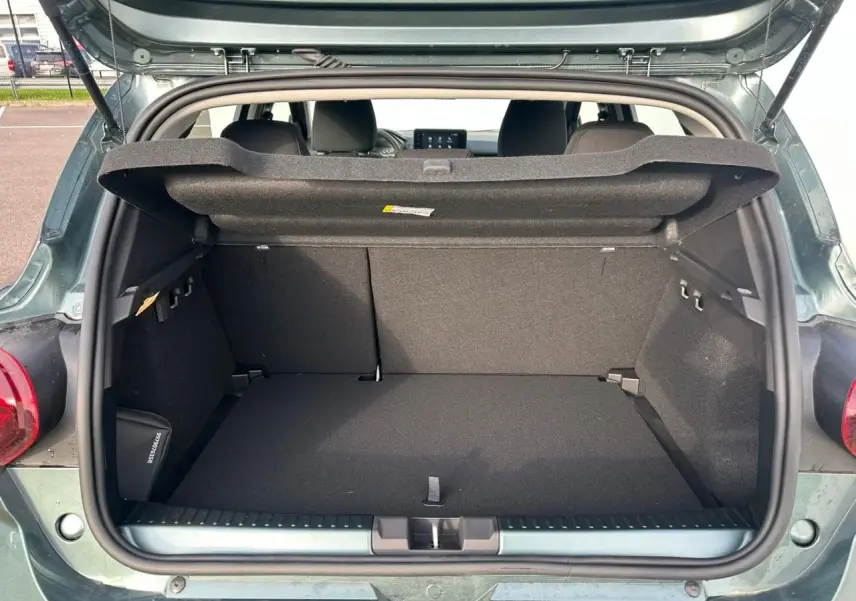 Coffre ouvert vu de l'arrière d'une Dacia Sandero III Stepway 2025 vert cèdre, intérieur noir et tablette de coffre relevée.