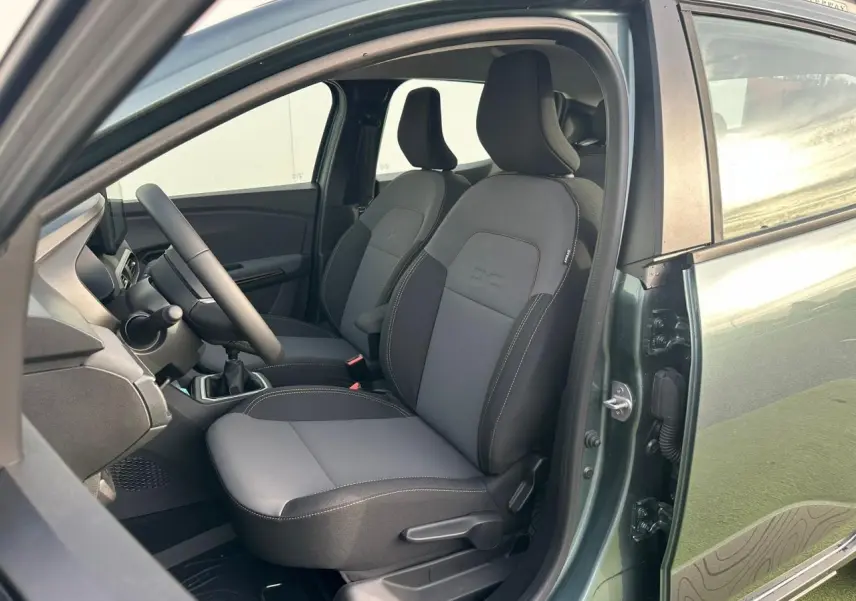 Vue côté gauche intérieur de la Dacia Sandero III Stepway 2025 vert cèdre, montrant les sièges avant et le volant.