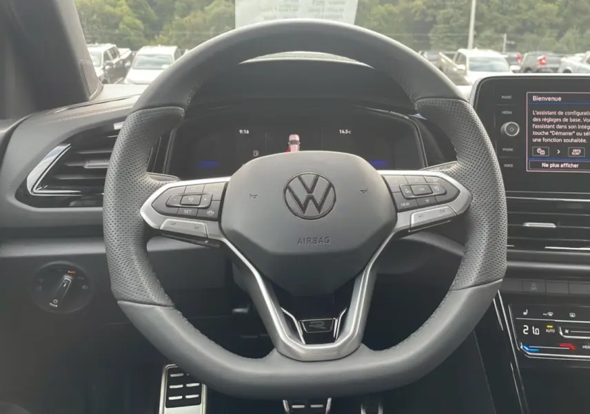 Vue intérieure centrée sur le volant cuir multifonctions du Volkswagen T-Roc noir grenadilla avec tableau de bord digital.