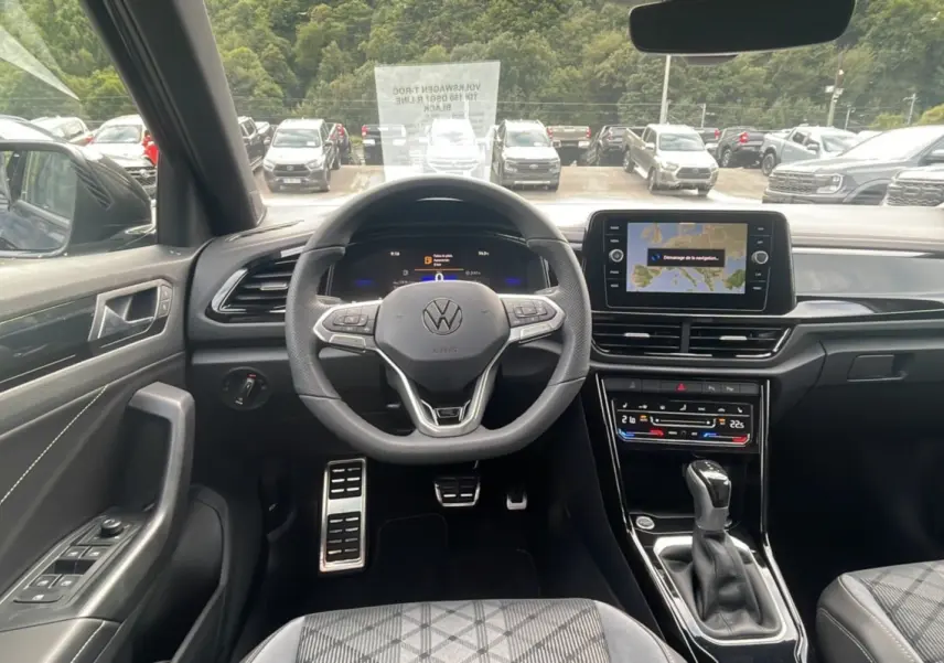 Vue intérieure avant du Volkswagen T-Roc TDI 150 DSG7 R-Line Black, volant cuir multifonctions et écran tactile GPS visible.