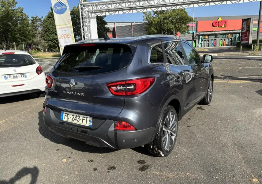 Vue 3/4 arrière droite d'un Renault Kadjar gris foncé garé, avec vitres surteintées et feux arrière LED distinctifs.
