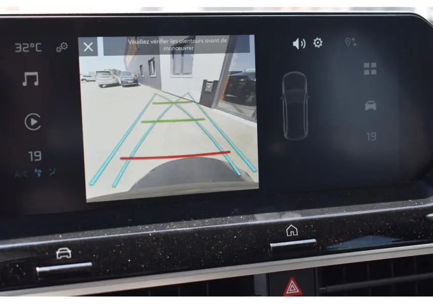 Écran central tactile montrant la caméra de recul d'une Citroën C4 Hybride noire, avec lignes de guidage colorées.