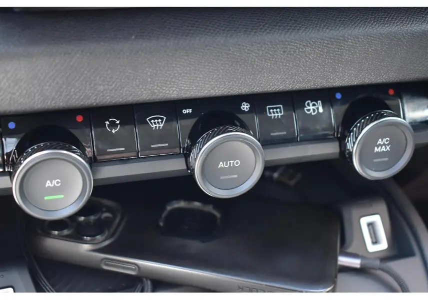 Gros plan sur les commandes de climatisation automatique de la Citroën C4 Hybride noire, avec boutons rotatifs et affichages LED.