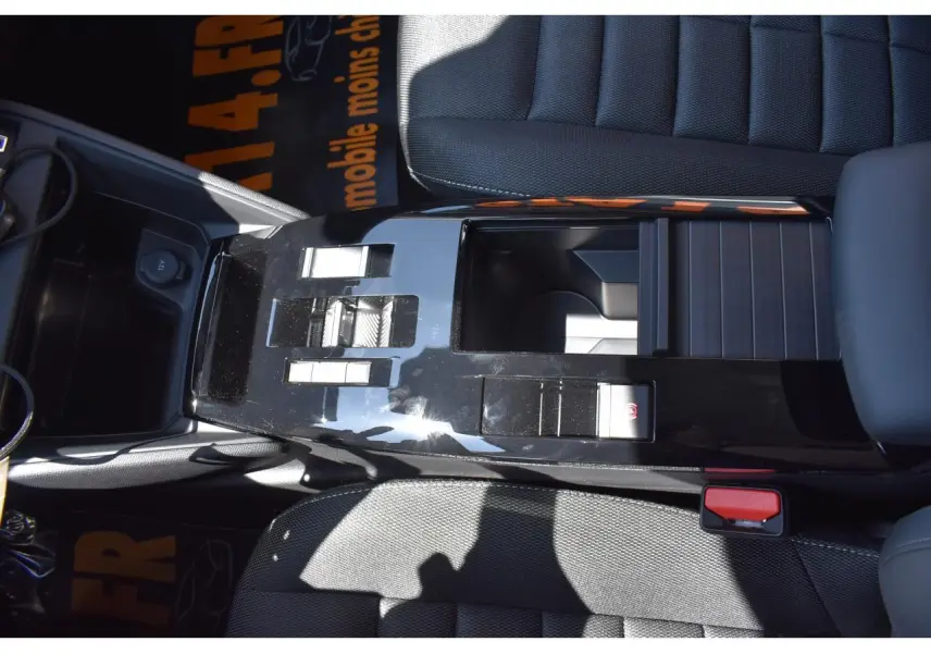 Vue plongeante sur la console centrale noire brillante de la Citroën C4 Hybride 136 e-DCS6 Plus avec sièges tissu gris.