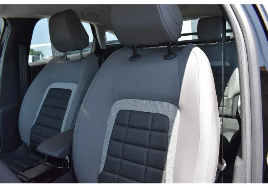 Gros plan sur les sièges avant gris et noirs du Citroën C4 Hybride 136 e-DCS6 Plus 2025, intérieur lumineux.