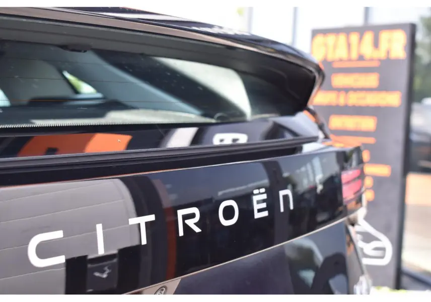 Gros plan sur l'arrière noir brillant d'une Citroën C4 hybride 2025 avec hayon ouvert et logo Citroën visible.