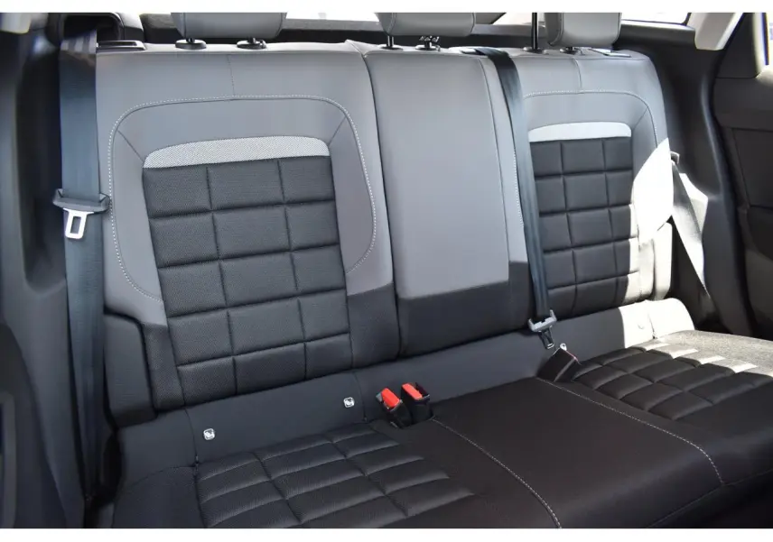 Vue rapprochée des sièges arrière en tissu noir et gris de la Citroën C4 Hybride 2025, avec ceintures de sécurité visibles.
