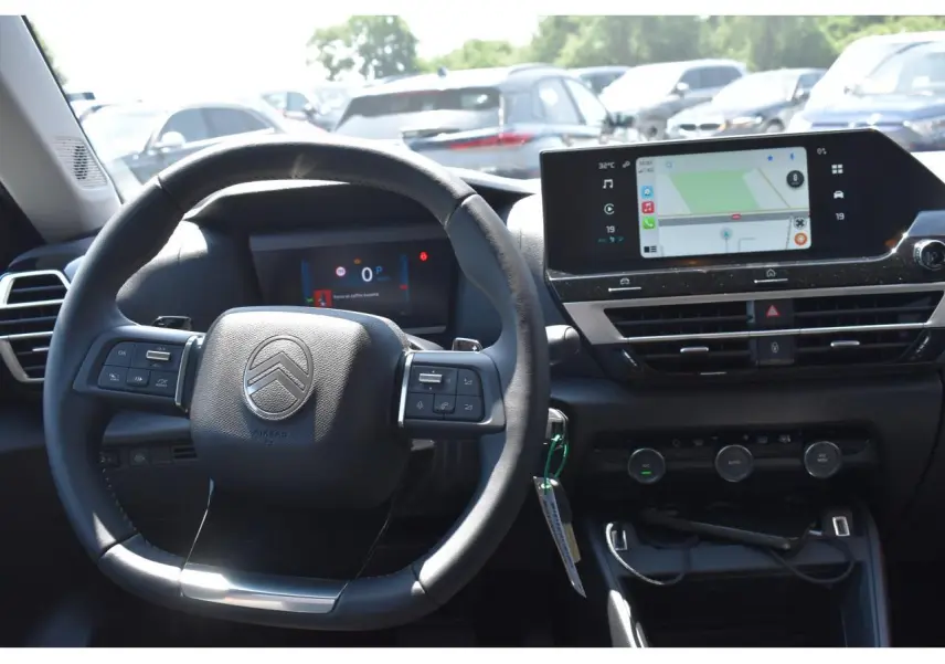 Vue intérieure centrée sur le volant et l’écran tactile du tableau de bord du Citroën C4 Hybride noir 2025.