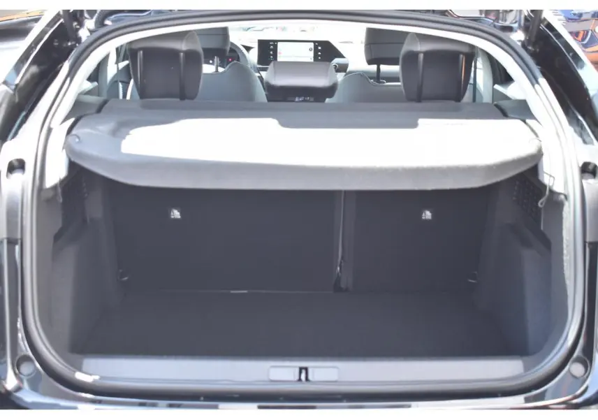 Vue arrière du coffre ouvert d'une Citroën C4 Hybride 136 e-DCS6 Plus noire, avec tablette cache-bagages et intérieur visible.