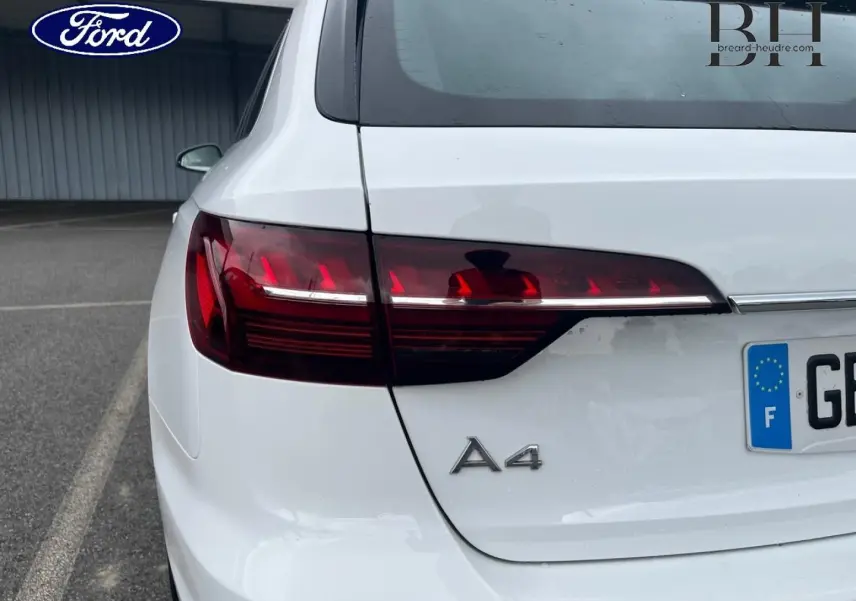 Vue arrière gauche d'une Audi A4 Avant blanc glacier métallisé avec feux arrière LED et logo A4 visible.