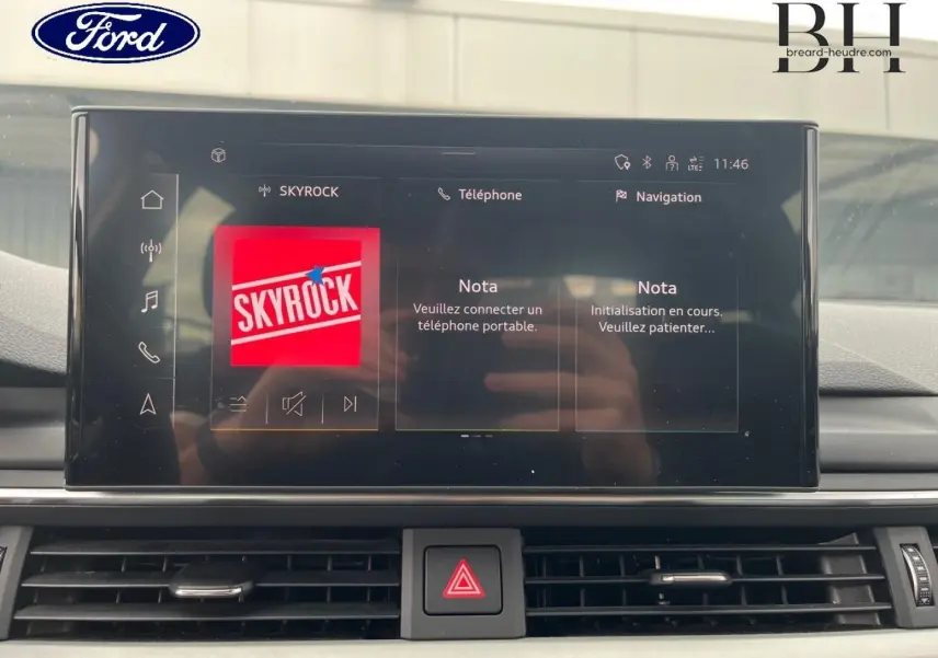 Vue rapprochée de l'écran tactile central de l'Audi A4 Avant blanc glacier, affichant l'interface multimédia Skyrock.