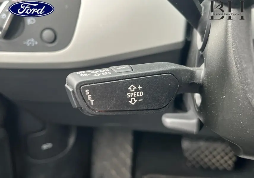 Gros plan sur la commande de régulateur de vitesse au volant d'une Audi A4 Avant blanc glacier métallisé.