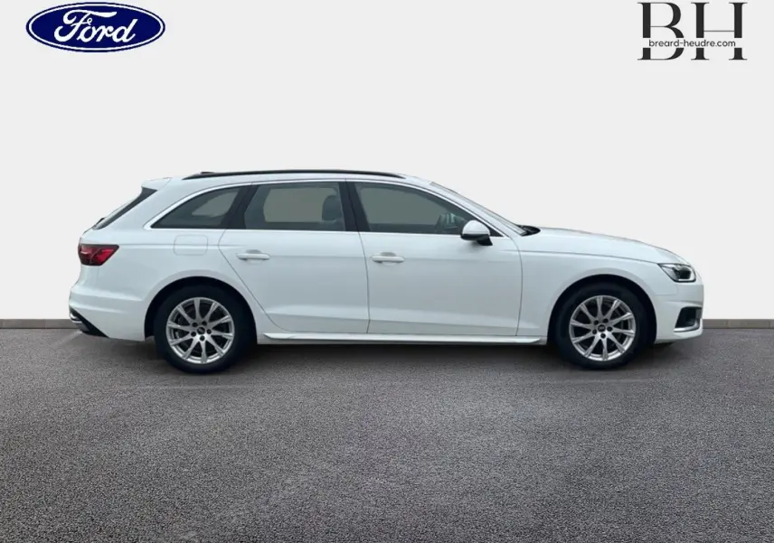 Profil droit d'une Audi A4 Avant blanc glacier métallisé, jantes alliage et barres de toit visibles.