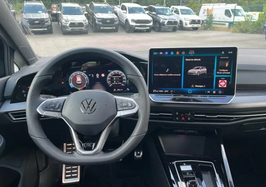 Vue intérieure centrée sur le volant cuir multifonctions et l'écran tactile du tableau de bord de la Volkswagen Golf noir ebène.
