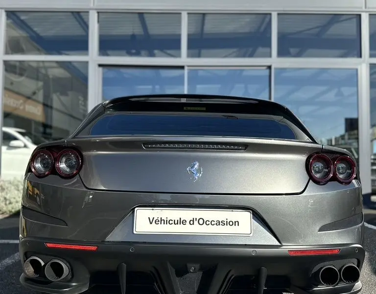 Vue arrière d'une Ferrari GTC4 Lusso gris foncé de 2017 avec double sortie d'échappement et logo au centre.