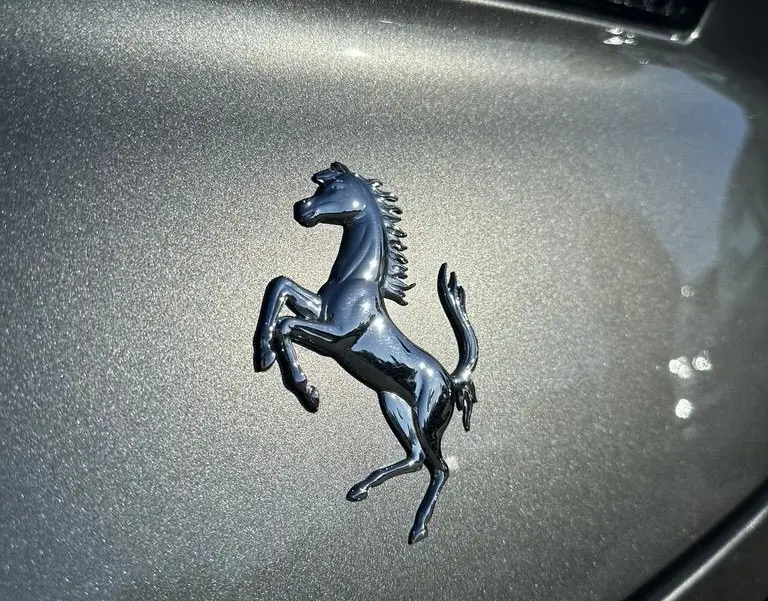 Gros plan sur l'emblème cheval cabré noir sur la calandre gris foncé d'une Ferrari GTC4 Lusso 2017.