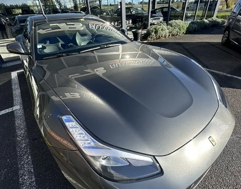 Vue 3/4 avant d'une Ferrari GTC4 Lusso gris foncé brillante, avec ses phares LED et son capot sculpté bien visibles.