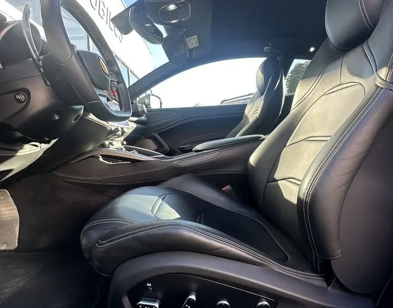 Intérieur côté conducteur de la Ferrari GTC4 Lusso 2017, sièges cuir noirs avec logo cheval cabré brodé sur appuie-tête.