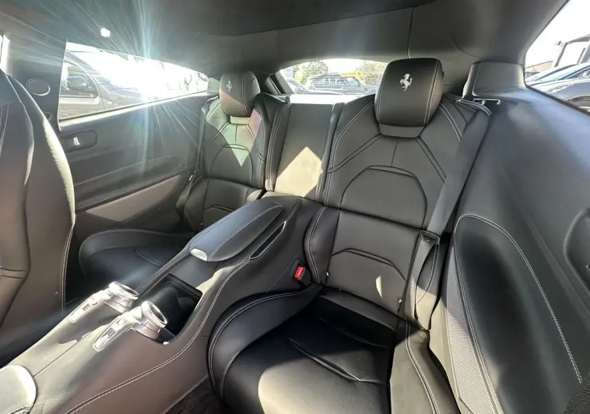 Vue intérieure arrière de la Ferrari GTC4 Lusso 2017, sièges en cuir noir avec logo brodé sur les appuie-tête.