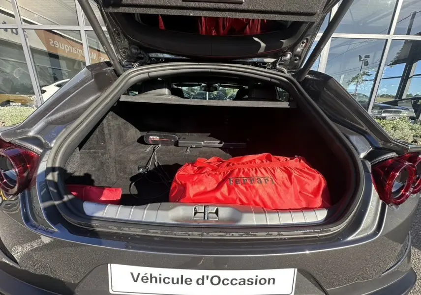 Vue arrière ouverte d'une Ferrari GTC4 Lusso gris foncé de 2017, coffre avec sac rouge Ferrari visible.