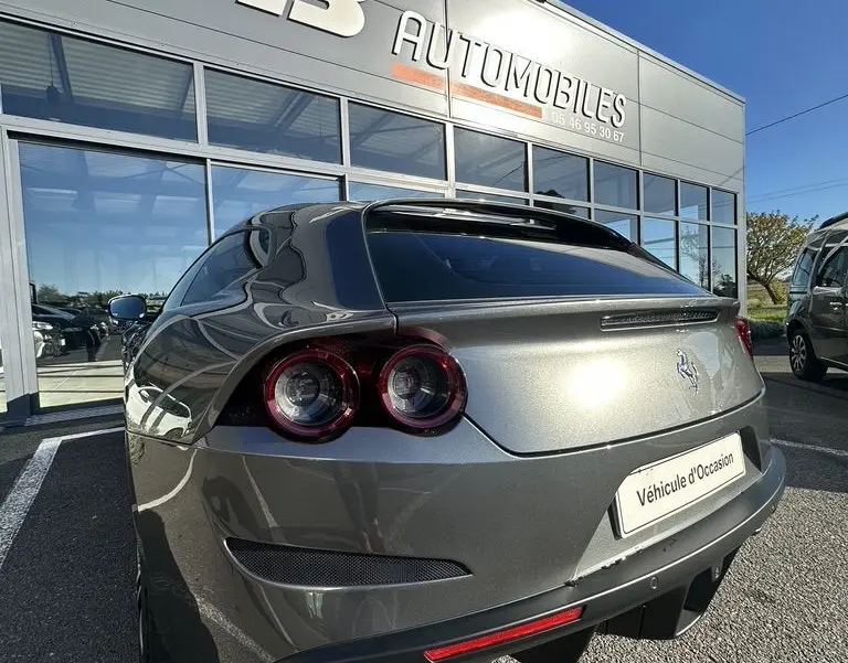 Vue 3/4 arrière droite d'une Ferrari GTC4 Lusso gris foncé avec feux ronds doubles et double sortie d'échappement.