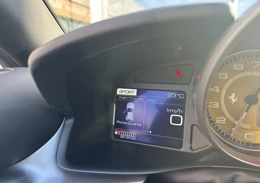 Tableau de bord de Ferrari GTC4 Lusso 2017 avec écran digital indiquant porte ouverte et compte-tours jaune visible.